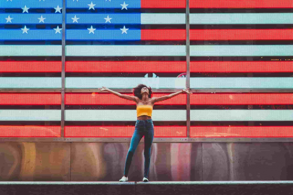 미국 국기 앞에 서 있는 한 여성.