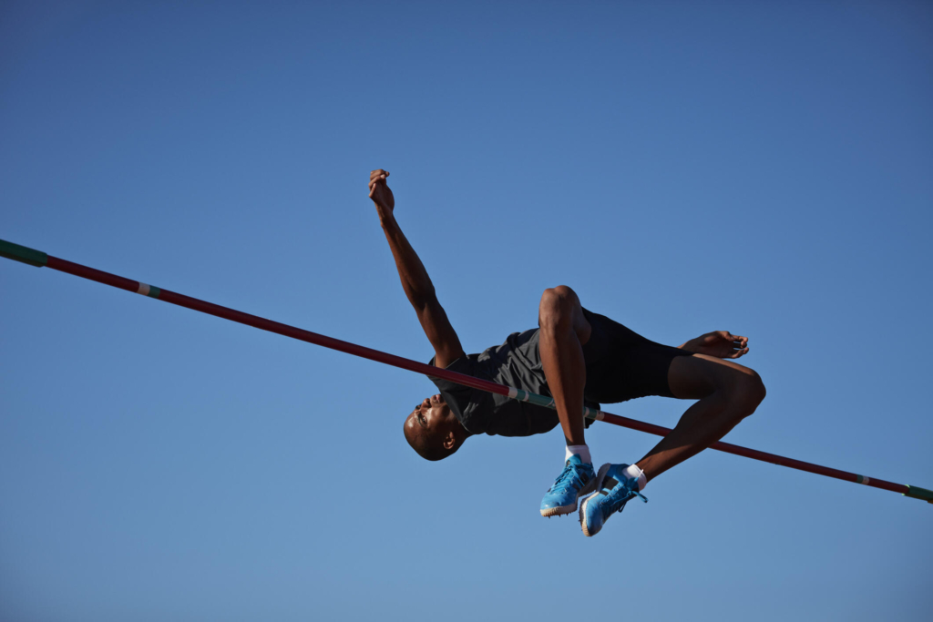 Male athlete executing a high jump, captured mid-air as he clears the bar.